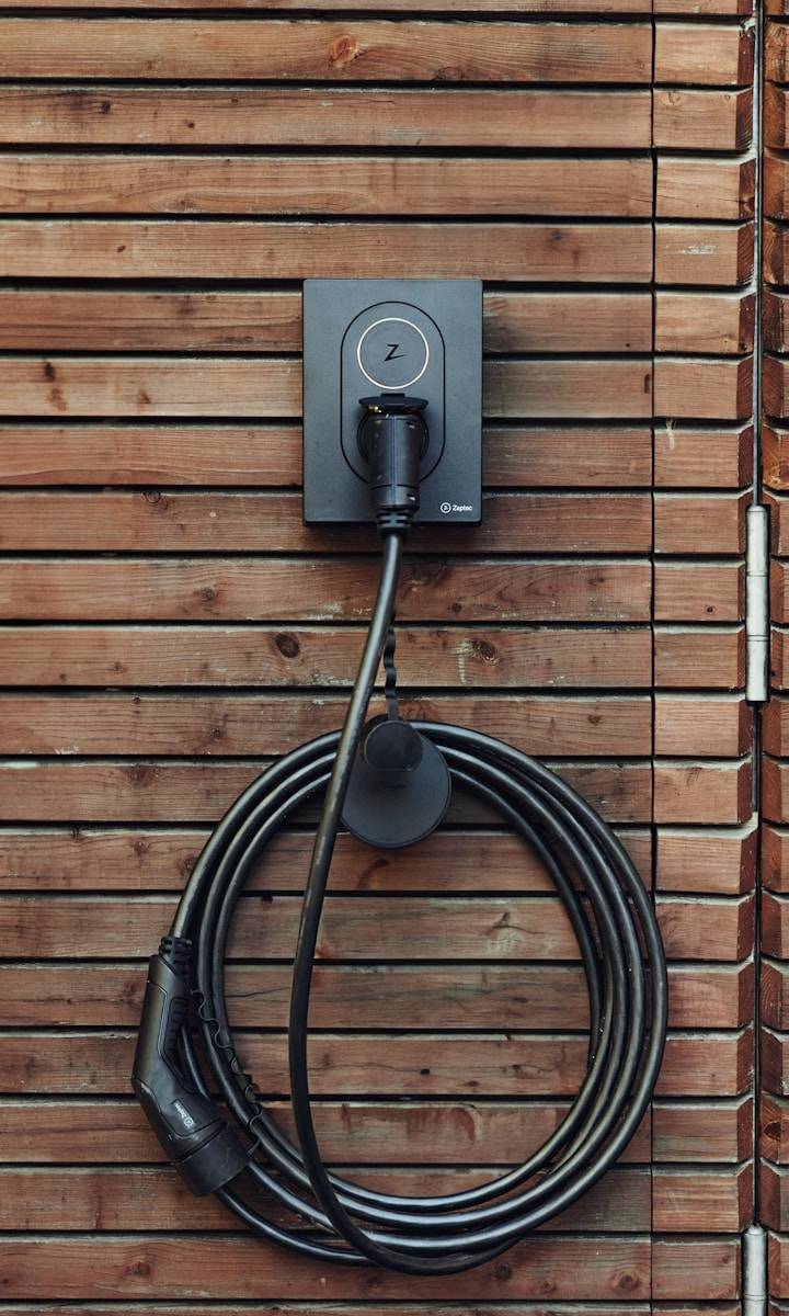 a black cord plugged into a wooden wall